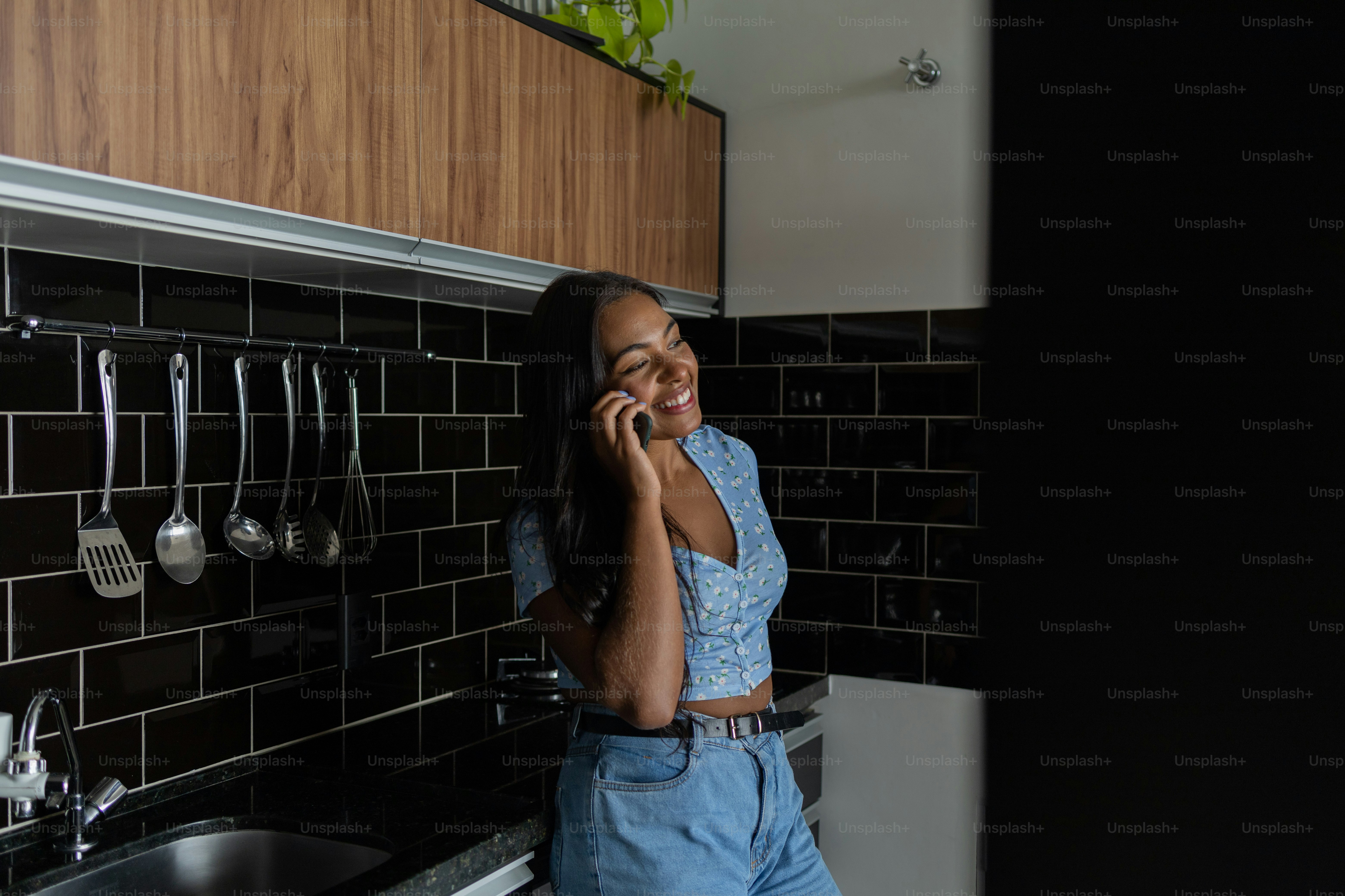 Young black woman working at home with smartphone in the kitchen of her ...