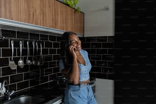 Young black woman working at home with smartphone in the kitchen of her apartment.  Home office concept.