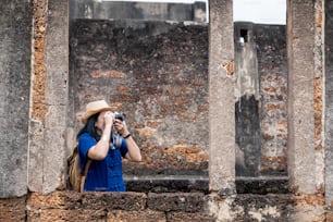La mujer turista asiática toma una foto de la arquitectura antigua del templo tailandés en Sukhothai, Tailandia. Viajera femenina en ropa tailandesa casual estilo visitando el concepto de la ciudad