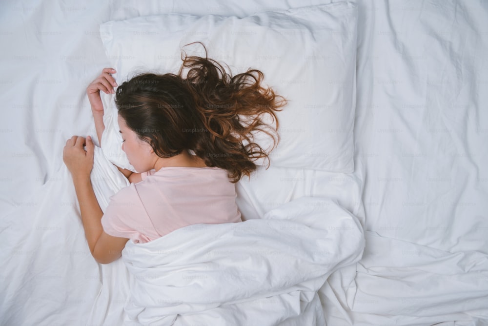 Adolescente qui dort en se reposant. concept de bonne nuit de sommeil. Une fille en pyjama dort sur un lit dans une chambre blanche le matin. ton chaud.