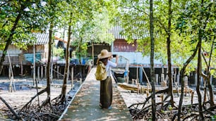 Die Mädchentouristen wandern beim Fotografieren Die Lebensweise der Dorfbewohner in ländlichen Dörfern Ban Bang Phat - Phangnga. Sommer, See, Urlaub, Reisen Thailand. Rucksack. Handy, Foto.
