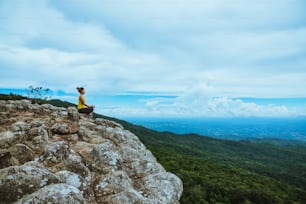 Donna asiatica rilassarsi in vacanza. Viaggia rilassati.  Gioca a fare yoga. Sulla scogliera rocciosa di Moutain. Natura delle foreste montane in Thailandia