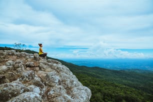 Asian woman relax in the holiday. Travel relax.  Play if yoga. On the Moutain rock cliff. Nature of mountain forests in Thailand