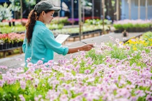 Las mujeres jóvenes que trabajan en el jardín de flores están estudiando y escribiendo registros de los cambios de los árboles de flores. Fondo del jardín de flores