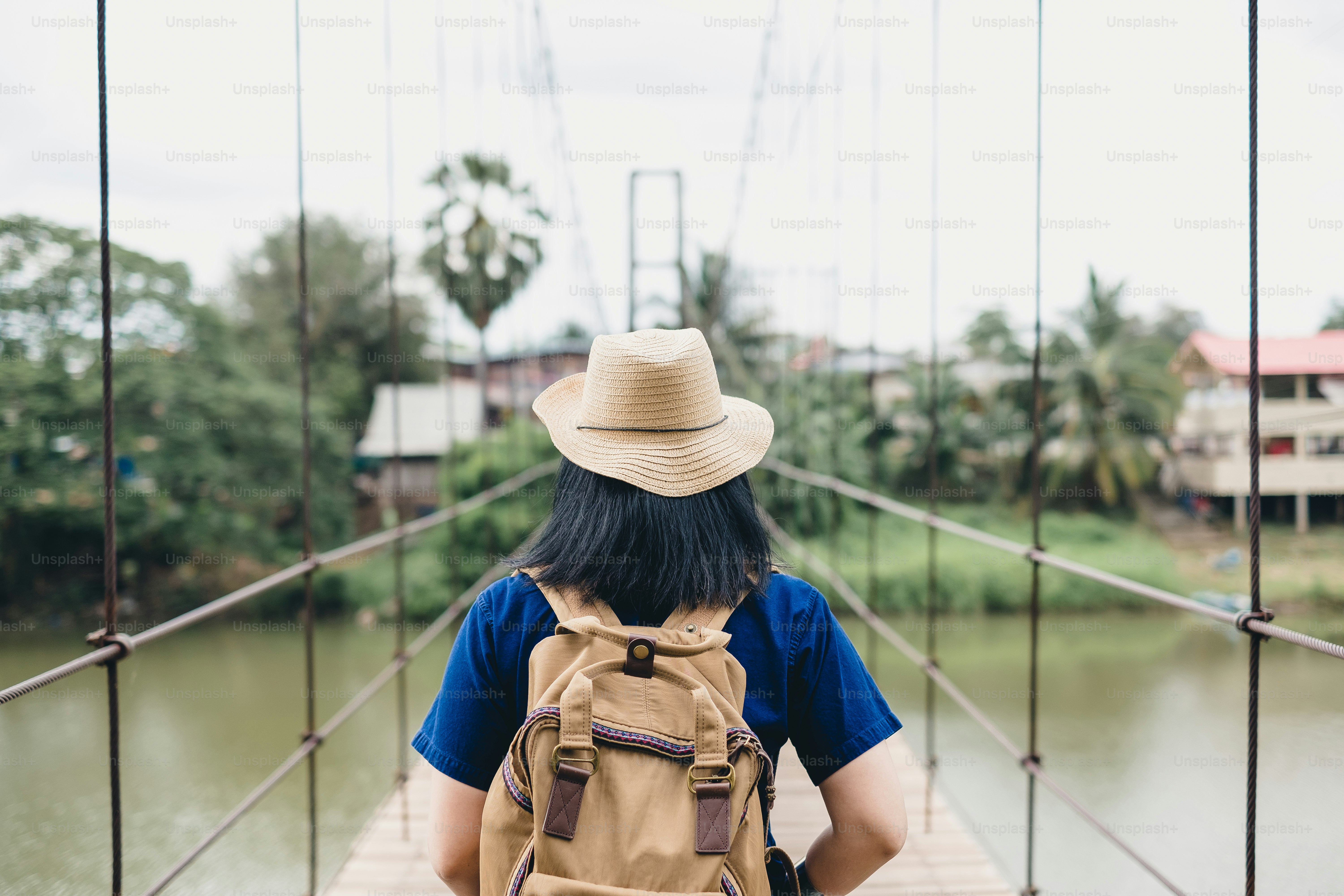 Traveler asian woman with backpack at foot bridge across river in countryside,Summer vacation traveling