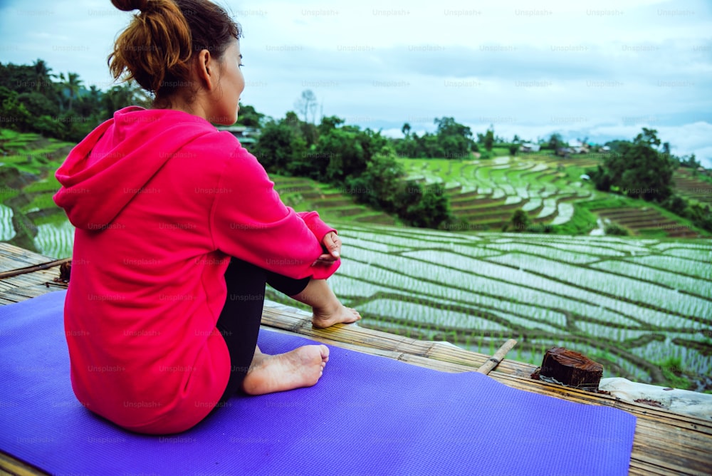 La mujer asiática se relaja en las vacaciones. Juega al yoga. En el balcón del paisaje del Campo Natural. papongpieng en Tailandia.