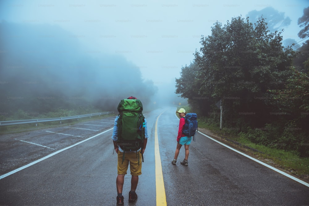 Amante del hombre asiático y las mujeres asiáticas viajan por la naturaleza. Camina por la ruta de la carretera. viajando felizmente por la naturaleza. En medio de la niebla lluviosa. en la temporada de lluvias.