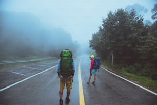 Lover asian man and asian women travel nature. Walk on the road route. traveling nature happily. Amid the mist rainy. in the rainy season.