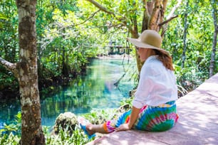 Asian women travel relax, travel nature in the holiday. Nature Study in the forest. women happy enjoying sitting and watching the lake mangrove forest. tha pom-klong-song-nam at krabi. summer