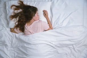 Adolescente durmiendo descansando. Concepto de sueño de buena noche. Chica en pijama duerme en una cama en una habitación blanca por la mañana. tono cálido.