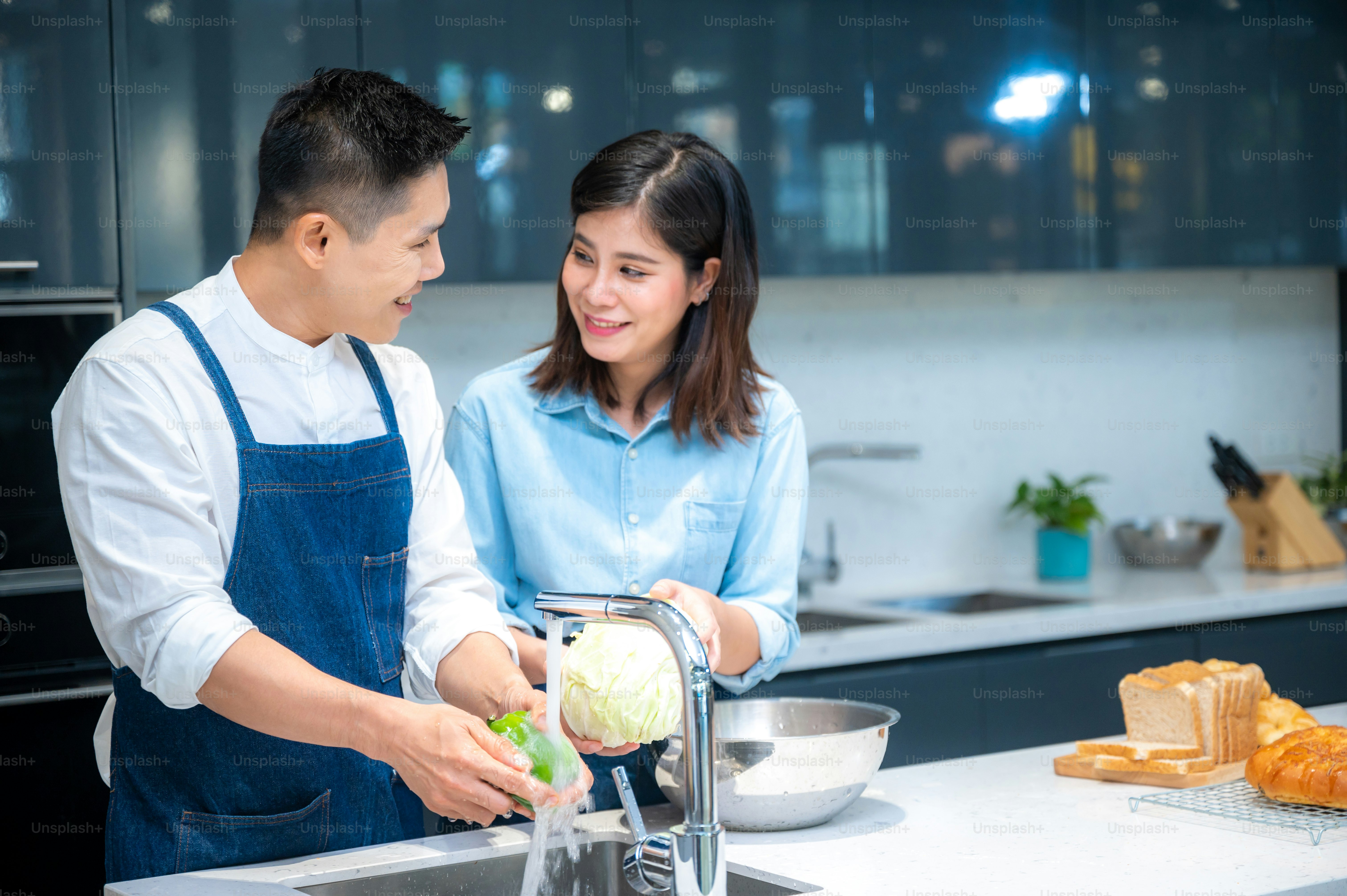 Portrait of happy young couple cooking together in the kitchen at home.