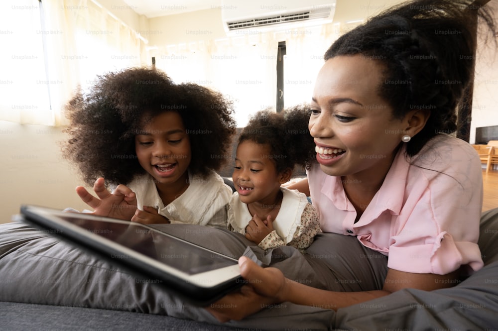 Felice famiglia bianca africana americana e caucasica che guarda la TV sul divano di casa, il concetto di famiglie di tutte le età si sta godendo le attività in casa.