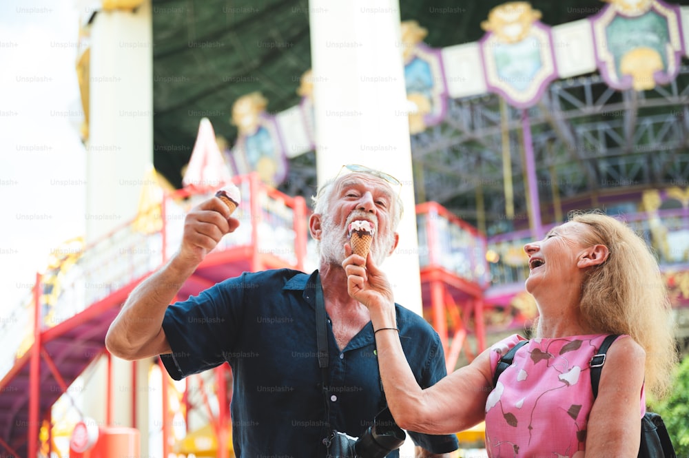 Senior couple relaxing at an amusement theme park, eating and enjoy with Ice cream on summer in concept of happy