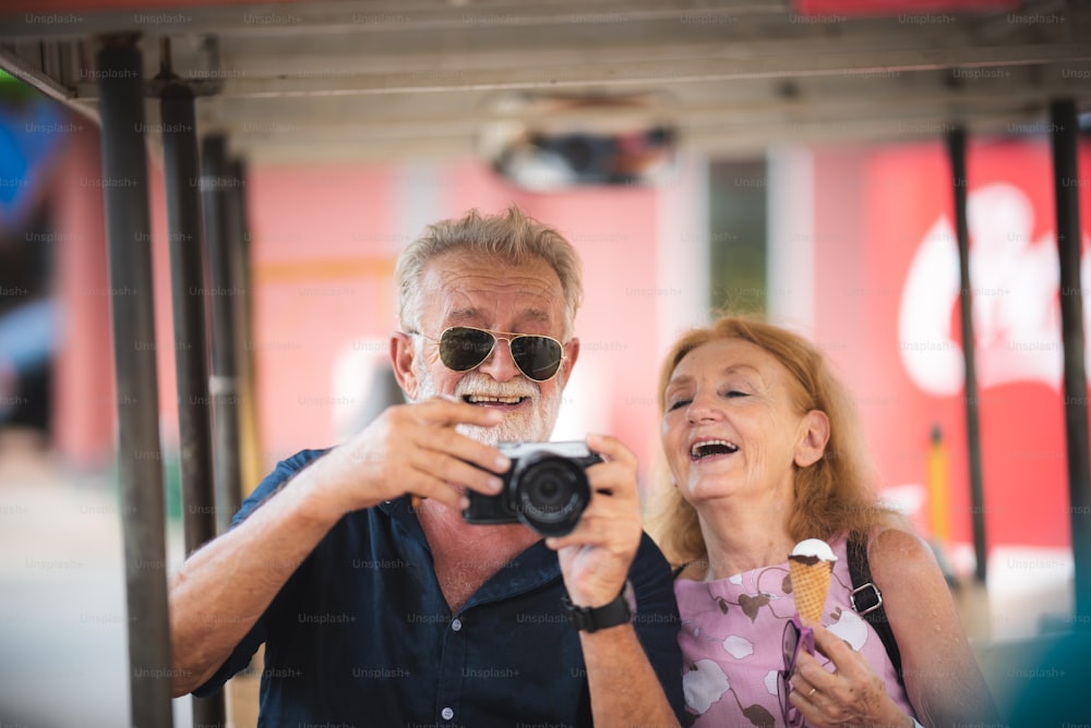 Senior couple taking a selfie at amusement theme park, Two old persons in the 60's having fun with camera relaxing and enjoy outdoor