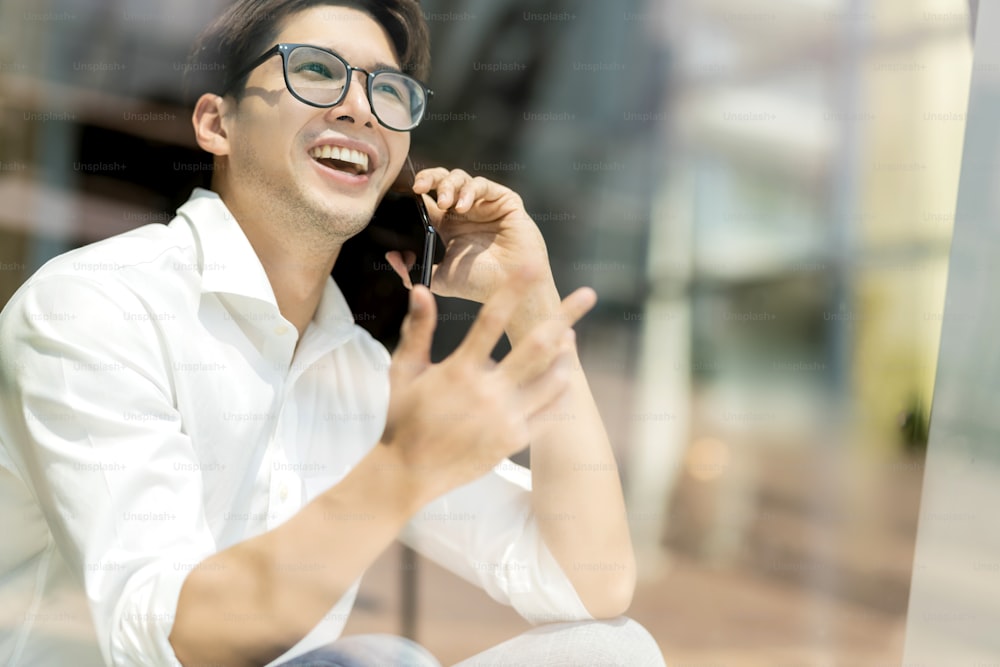 Smart attractive positive asian business male wearing glasses work remote new normal lifestyle hand use smartphone conference onlive videocall meeting remote business ideas concept shot through window