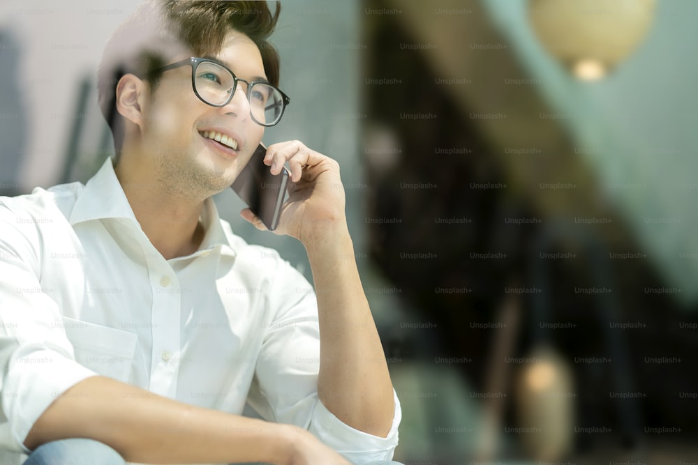Smart attractive positive asian business male wearing glasses work remote new normal lifestyle hand use smartphone conference onlive videocall meeting remote business ideas concept shot through window