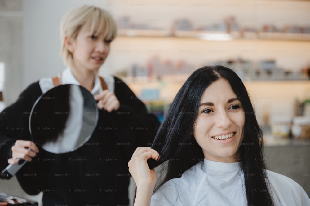 coiffeur professionnel et femme caucasienne cliente utilisant et regarder un miroir dans le salon, coiffure traitement de beauté des cheveux façonné, fille heureuse ayant une coupe de cheveux, service de style de soins capillaires dans le salon de coiffure