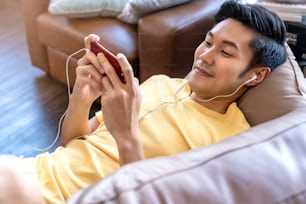 若いアジアの男性の手がスマートフォンゲームをオンラインでプレイするカジュアルでレジャーの終了と自宅での週末のソファでのJPYFULレイダウン検疫活動のアイデアコンセプト
