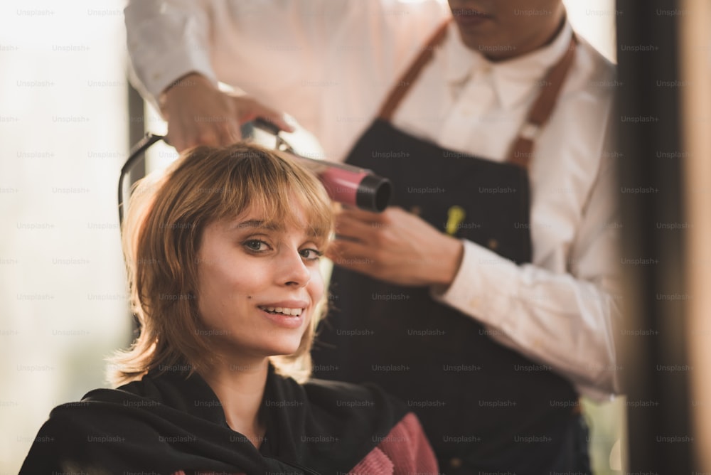 プロの美容師、スタイリストの人と髪のファッション美容院のコンセプト、ヘアカットとヘアケア、髪型理髪店の機器、ヘアスタイリストの仕事についての女性のクライアント、女性モデルに髪型を作る