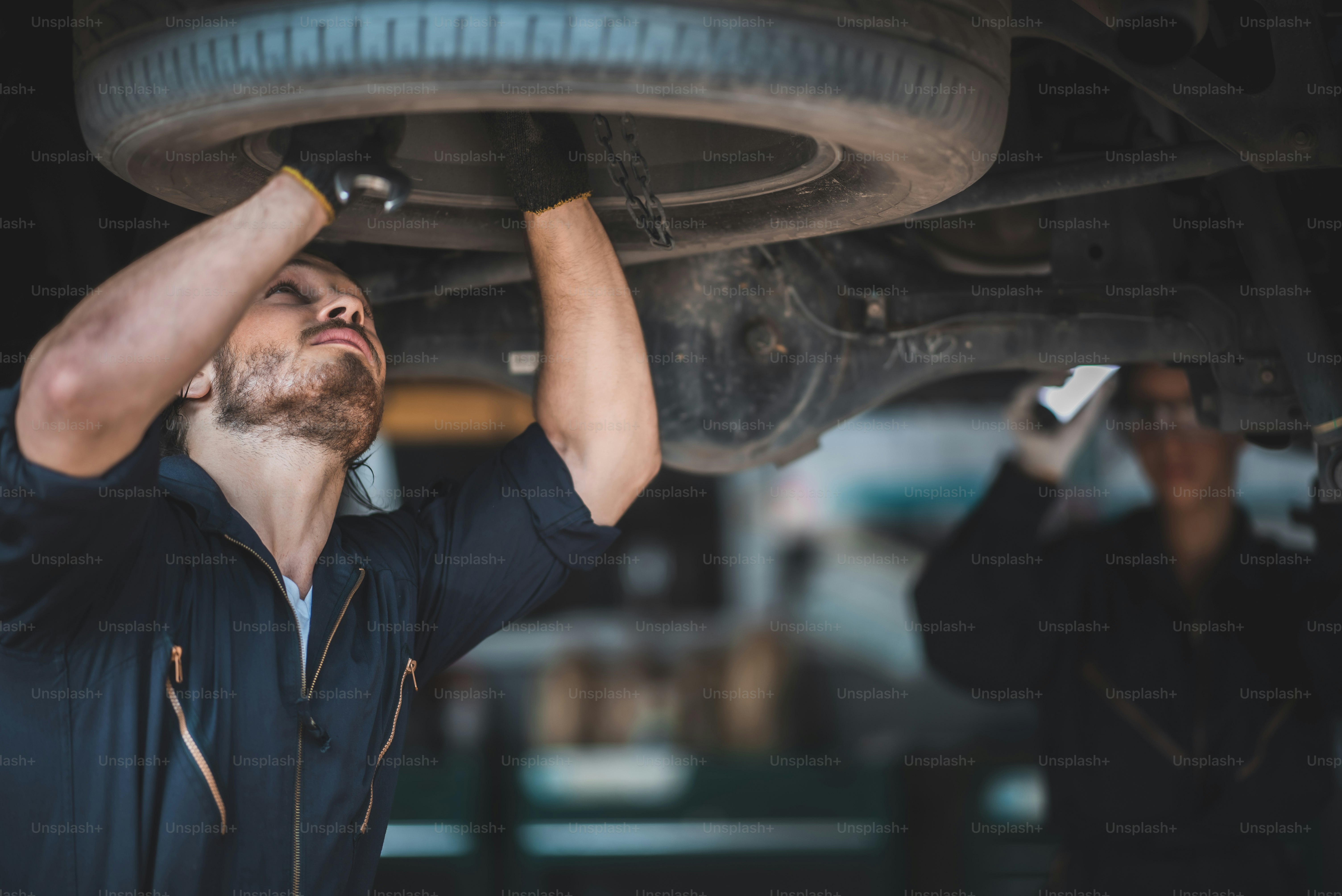Mechanic inspecting suspension under lifted car