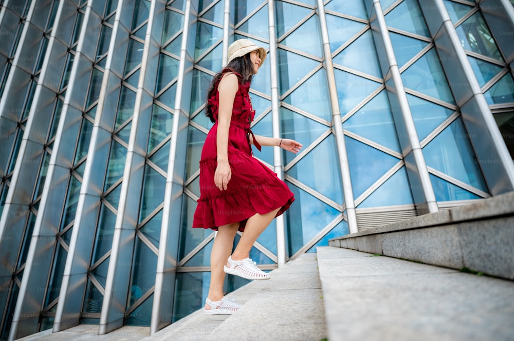Mulher asiática no vestido vermelho no edifício moderno, menina feminina com estilo de vida urbano da cidade