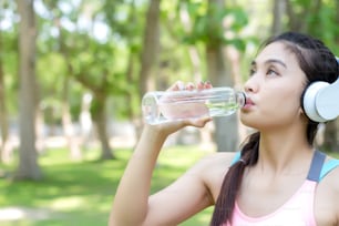 Asian young woman drinking water after workout exercising.