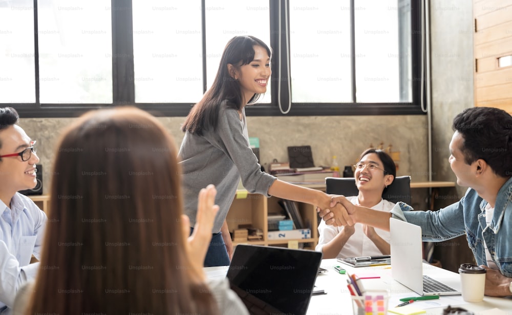 Asiatische Geschäftsleute smart casual tragen schüttelnde Hände bei der Arbeit im Kreativbüro. Business Team Kreatives Konzept