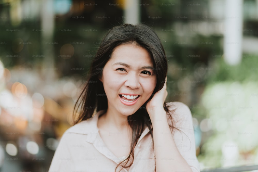 Schöne junge glückliche asiatische Frau, die im Freien lächelt und lacht