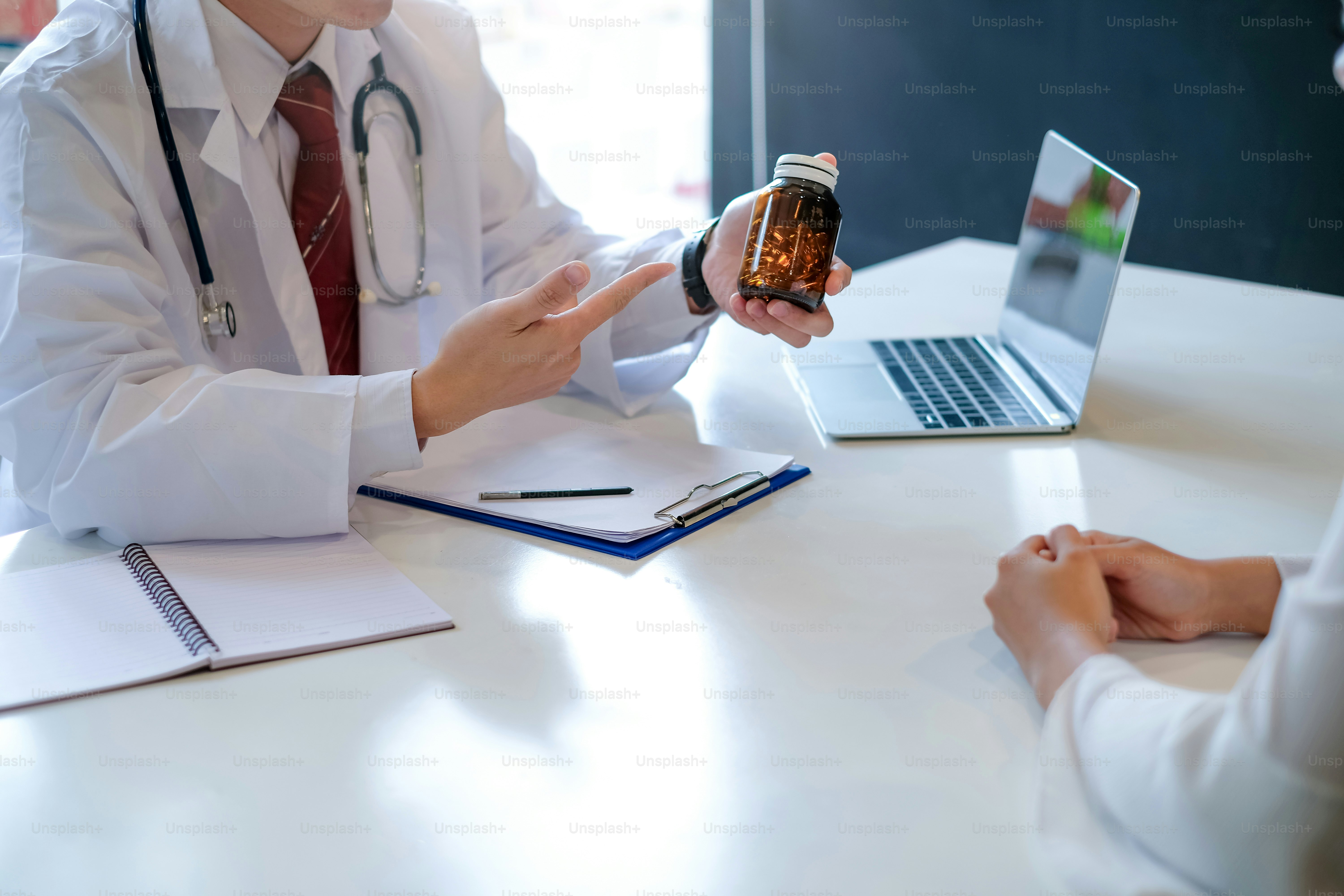 Männlicher Arzt erklärt und gibt Medizinflasche zum Patienten.