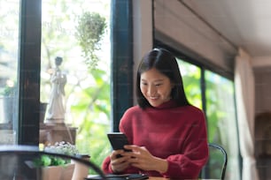 Young Asian girl using phone at a coffee shop .Woman happy on smartphone in cafe