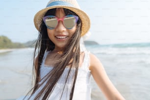 カメラの幸せな休暇のコンセプトを見ている海のビーチでポートレートの小さなアジアの女の子