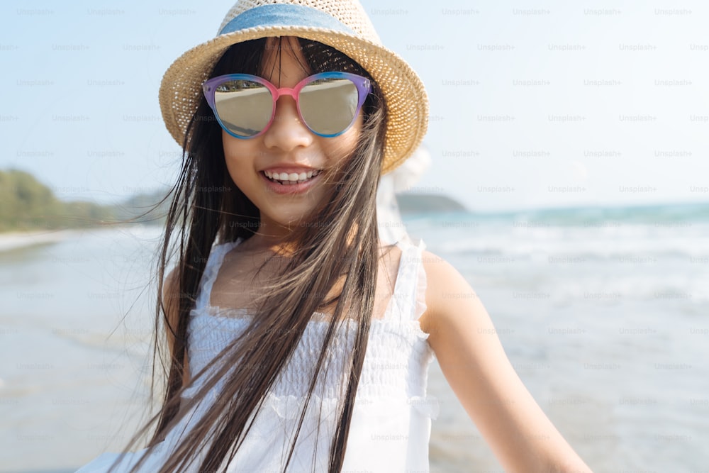 Portrait little Asian girl at sea beach looking at camera happy vacation concept
