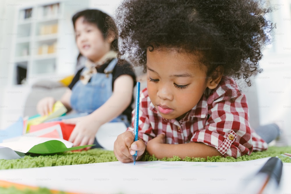 Group of little preschool kids drawing paper with color pencils . portrait of African girl with friends education concept.