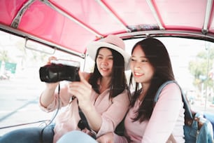 툭툭 택시로 여행하는 동안 카메라로 사진을 확인하는 두 명의 아시아 여성 여행자