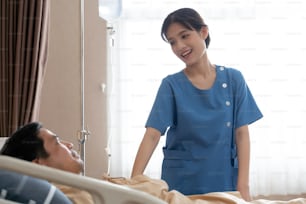 Enfermeira asiática conversando com paciente na enfermaria do hospital