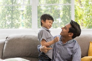 Happy son playing with father in living room. Asian family portrait concept