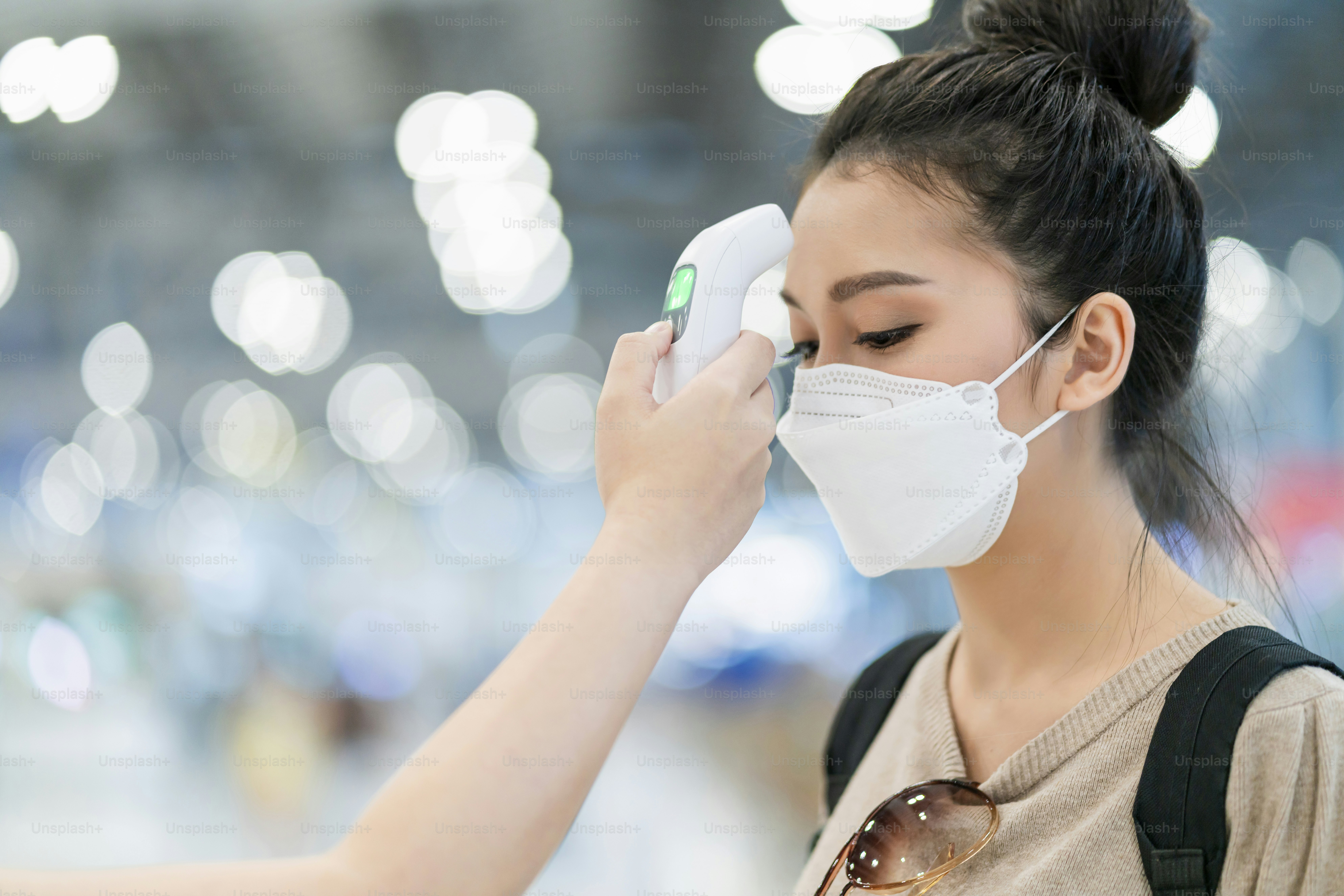 safety travel new normal lifestyle,asian female traveller wear casual cloth temperature check detect covid-19 at airport terminal before going abroad travel with blur airport departure terminal