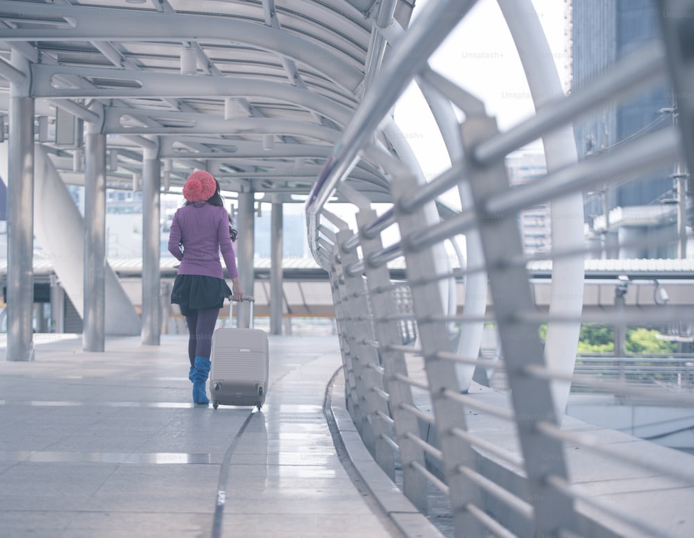 Zurück Ansicht Weibliche Reisende zu Fuß mit Koffer im Flughafenkorridor