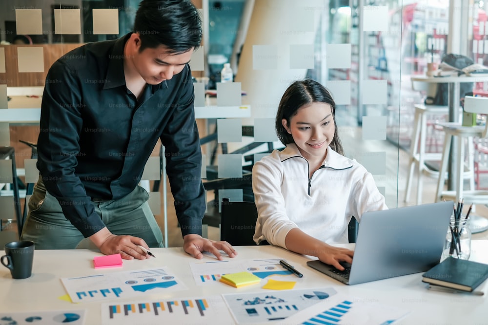 Two asian businessman and businesswoman discussing and working together in the office. Creative business team sitting working together at office.