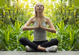 Asiatisch Schöne Frau, die Yoga in der Gebetsposition im Wald praktiziert.