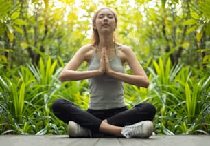 Asian Beautiful woman practicing yoga in the prayer position in the forest.