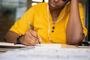 Stressed African FeMale Creative Designer in yellow shirt sitting and thinking new ideas on brick wall background.