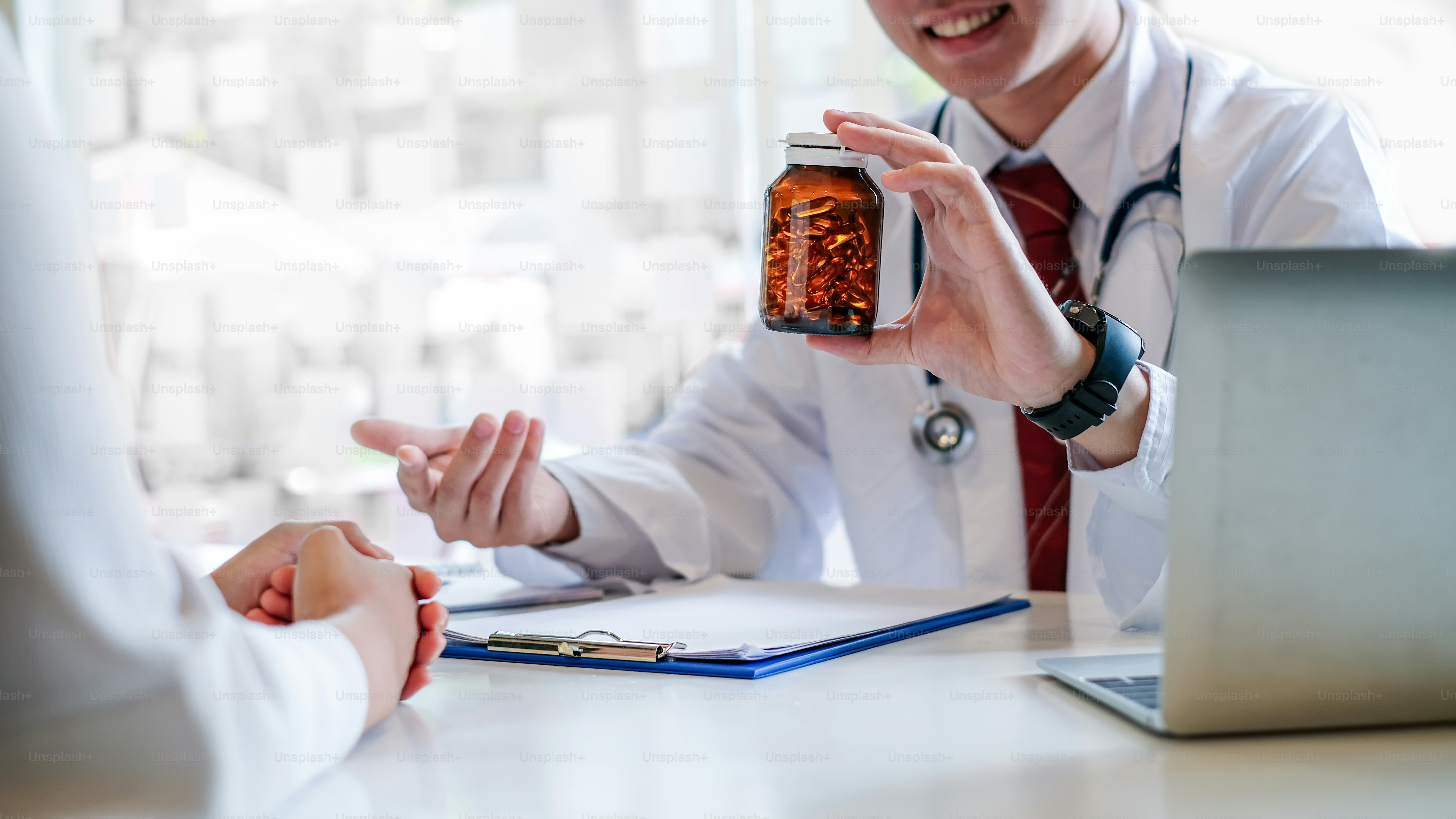 Young male doctor giving a pill bottle to a female patient in a clinic