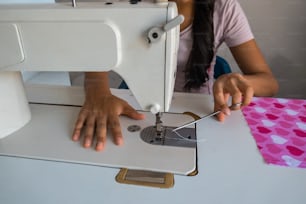 mulher nova que usa a máquina de costura enquanto trabalha na alfaiataria