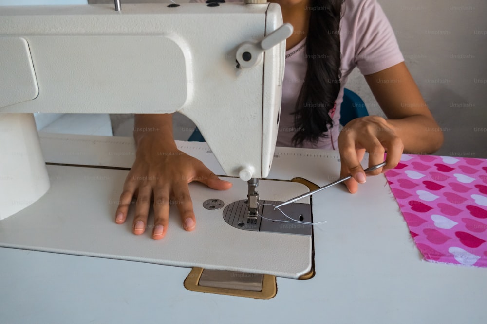 mujer joven usando la máquina de coser mientras trabaja en la sastrería