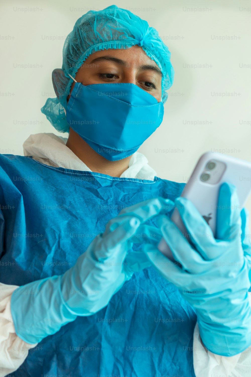휴대 전화를 사용 하 여 병원에서 보호 얼굴 마스크를 가진 여성 의사