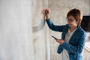 Creative woman in blue shirt drawing on the wall.