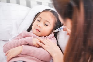 Mother using thermometer with her girl kid daughter for sickness and fever
