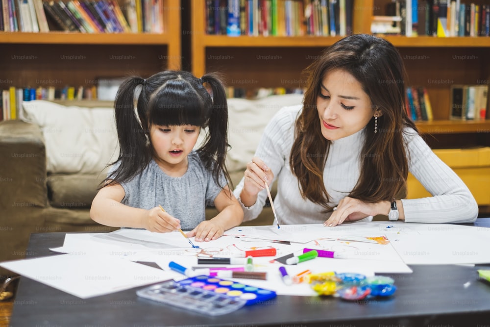 Asiatisches Mädchen Kind und Mutter beim Zeichnen mit vielen Farbstiften auf weißem Papier