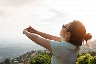 Asiatische Frau streckt ihre Arme auf dem Gipfel des Berges im Freien. Rückansicht. Urlaub, Urlaub und Gesundheit.